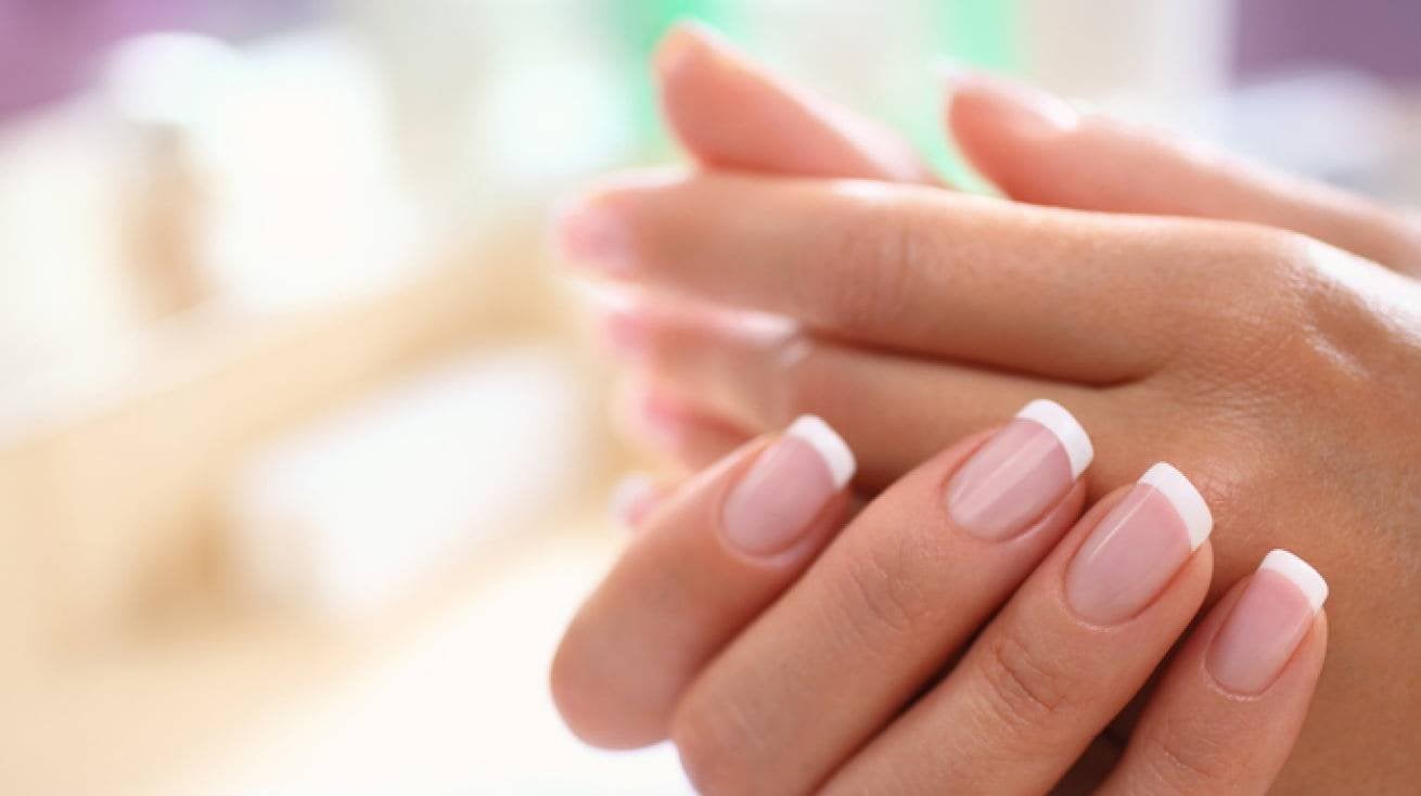 Hands with French manicure against blurred background