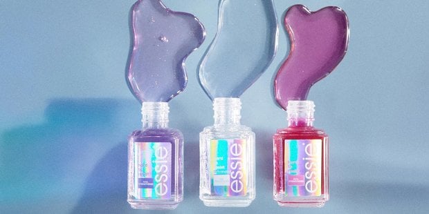 Trois bouteilles de fortifiants et de traitements pour les ongles essie se déversant sur un fond bleu